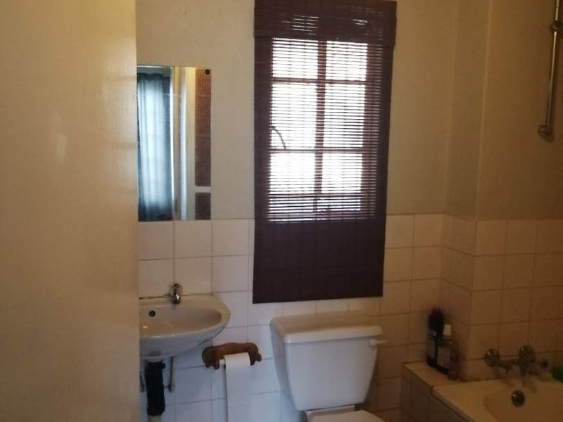 A functional bathroom featuring a pedestal basin, toilet, and bathtub with tiled finishes, offering potential for modernization and cosmetic updates.
