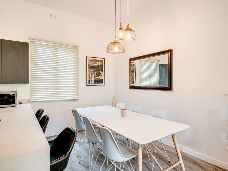 Open-plan dining area featuring modern pendant lighting, laminate flooring, and a built-in kitchen hob, creating a bright and functional living space.