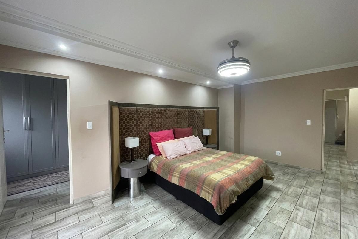 Spacious bedroom featuring tiled flooring, recessed downlighting, crown molding, a ceiling fan, and built-in cupboard storage.