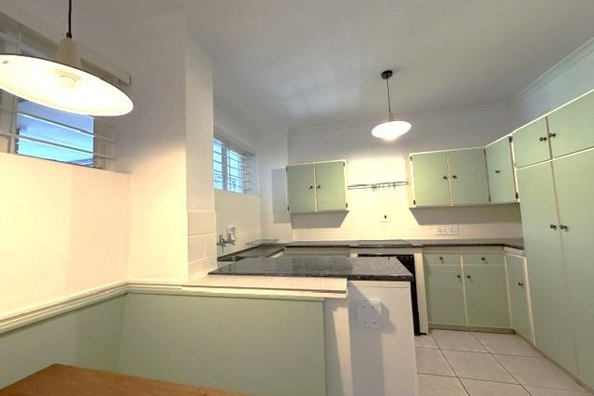 A functional kitchen featuring light green built-in cabinetry, laminate countertops, and tiled flooring, offering a clean space ready for modern updates.