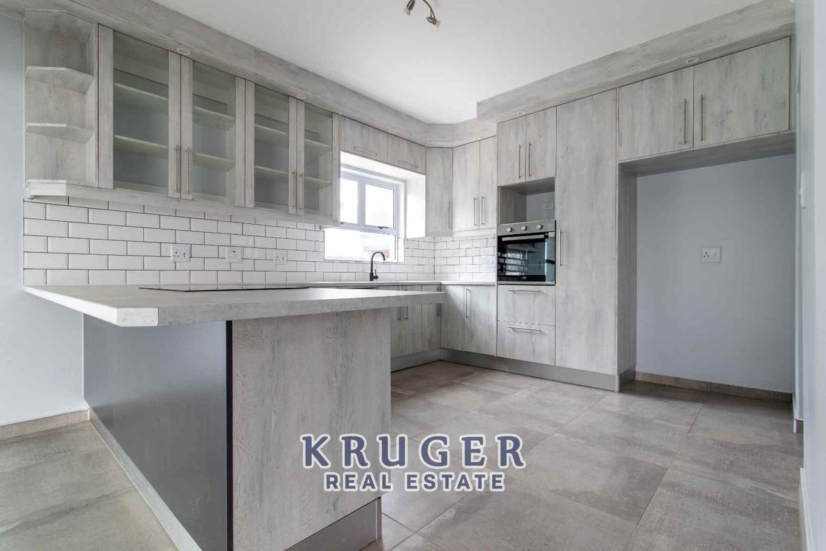Modern kitchen featuring light wood-grain cabinetry, subway tile backsplash, built-in oven, and a breakfast bar counter.