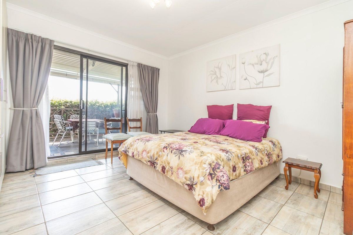 Spacious bedroom featuring tiled flooring and large sliding glass doors providing direct access to a private patio area.