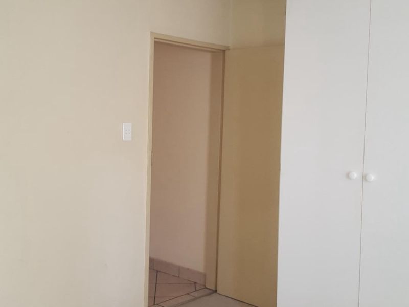 An empty bedroom featuring neutral wall finishes, built-in wardrobe storage, and carpet flooring.