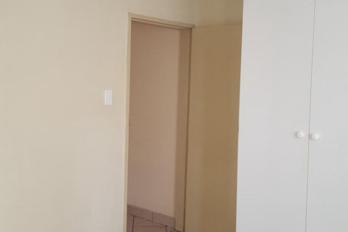 An empty bedroom featuring neutral wall finishes, built-in wardrobe storage, and carpet flooring.