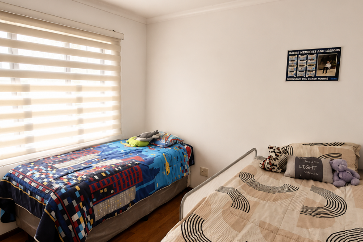 A bedroom featuring timber-look flooring, a flush-mount ceiling light, and a window fitted with modern zebra-style roller blinds.