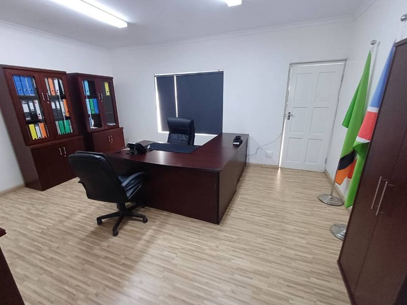 A functional office space featuring laminate flooring, neutral walls, and integrated lighting, suitable for a professional business environment.