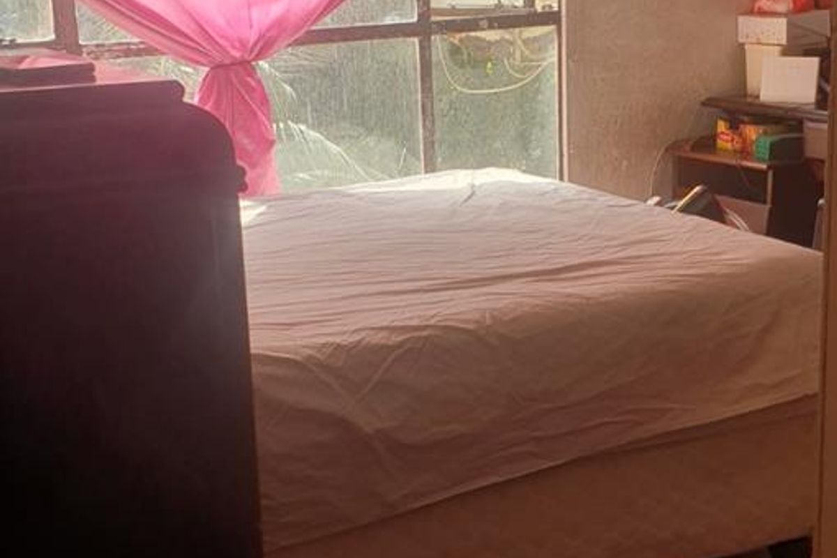 A bedroom featuring a large window with natural light, requiring cosmetic updates to the wall finishes and window frames to improve the overall condition.