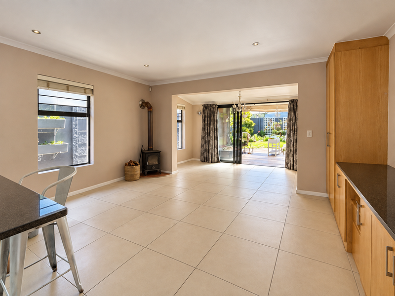 Spacious open-plan living area featuring tiled floors, built-in cabinetry with granite countertops, a cozy fireplace, and seamless access to the outdoor patio.