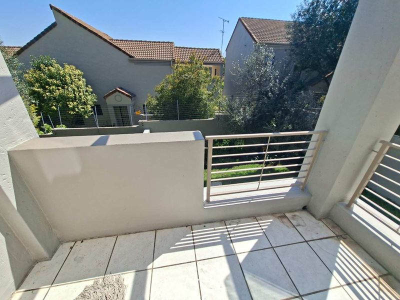 A private balcony featuring tiled flooring and a metal balustrade, offering an open view of the surrounding residential complex.