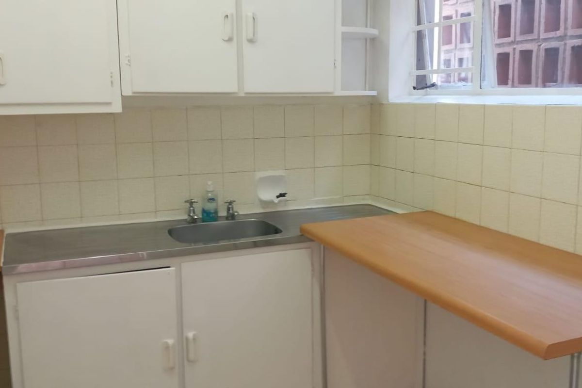 A functional kitchen area featuring laminate countertops, a stainless steel sink, and wall-mounted cabinetry with a tiled backsplash.