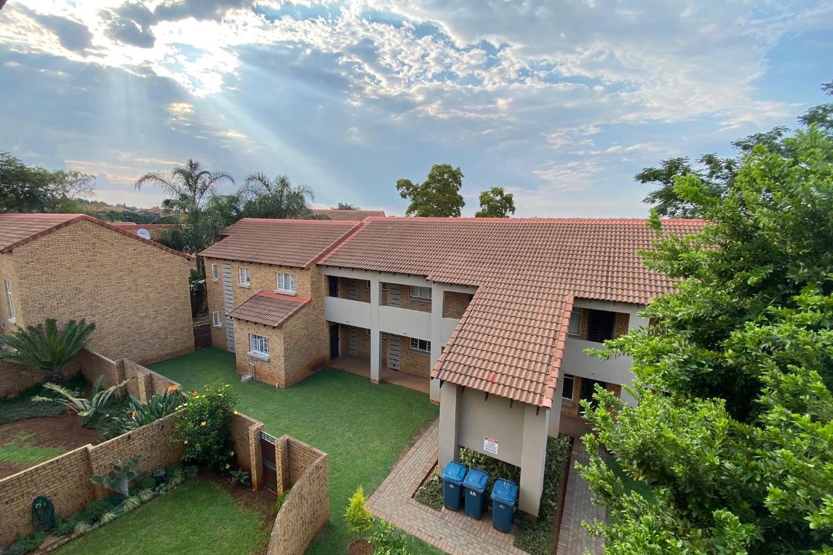 An elevated view of the townhouse complex, showcasing the tiled roof architecture, communal garden areas, and paved walkways.