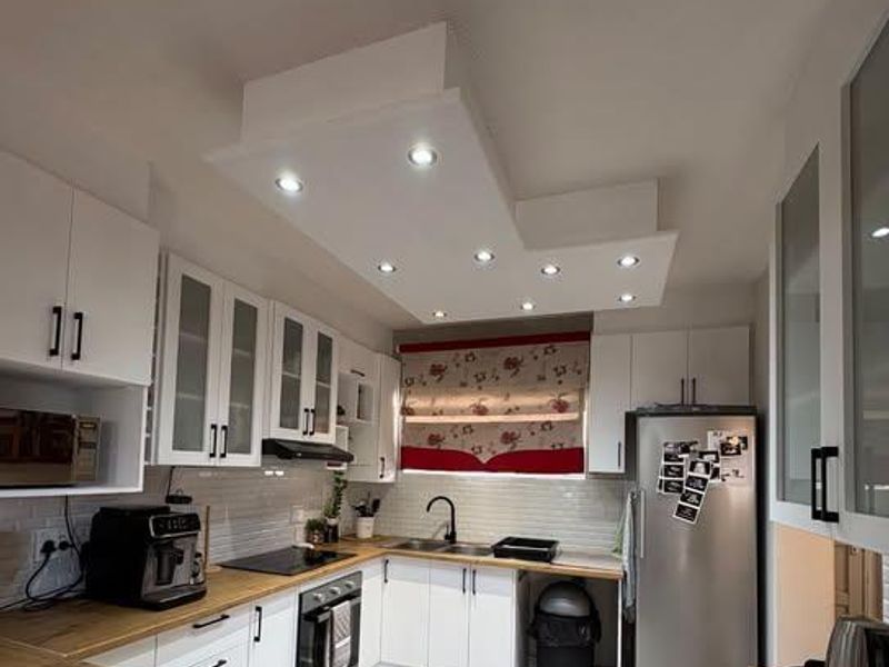 Modern kitchen featuring white cabinetry, wooden countertops, subway tile backsplash, and integrated appliances with recessed ceiling lighting.