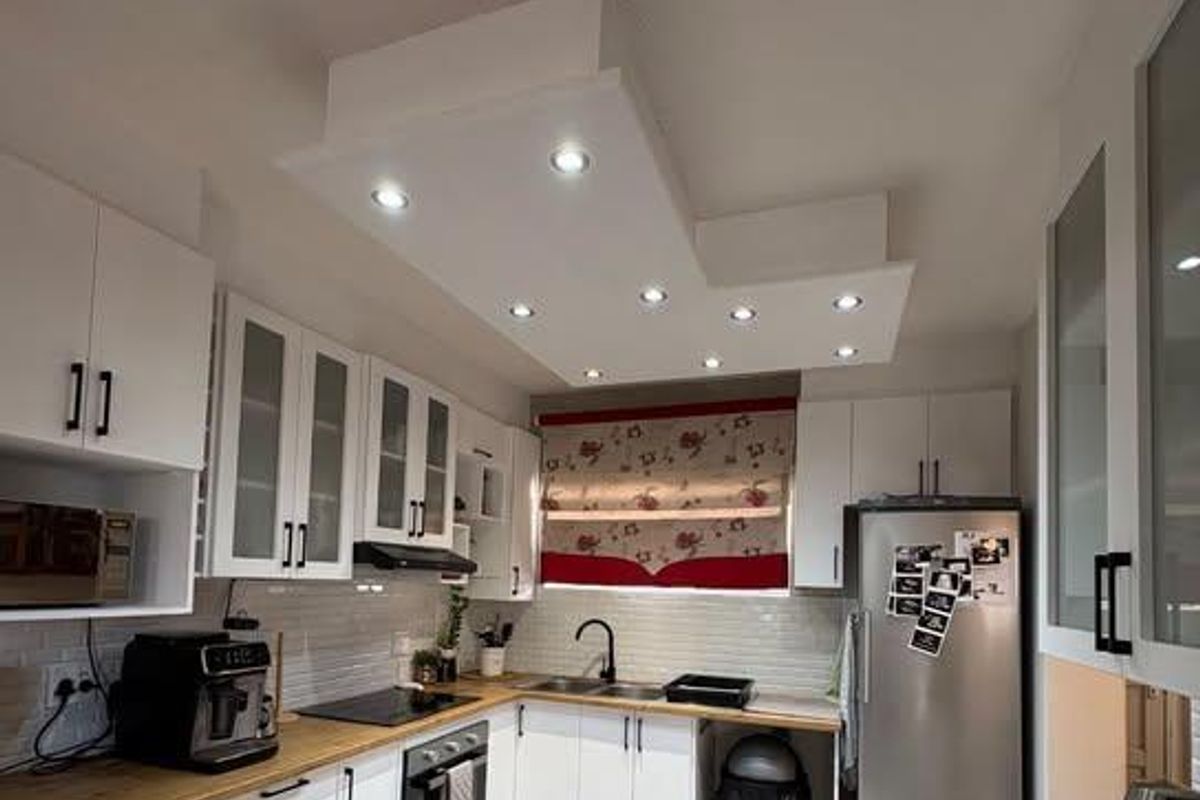 Modern kitchen featuring white cabinetry, wooden countertops, subway tile backsplash, and integrated appliances with recessed ceiling lighting.