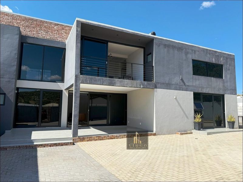 Modern two-story rear elevation featuring large sliding glass doors, a covered patio, and an upper-level balcony with metal railings.