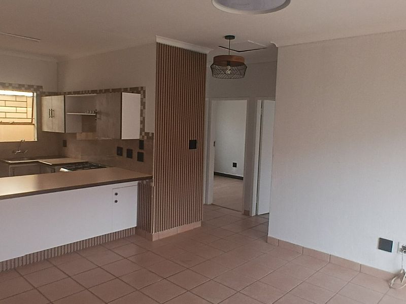 Open plan living and kitchen area featuring tiled floors, a breakfast bar, and a modern slatted wood feature wall.