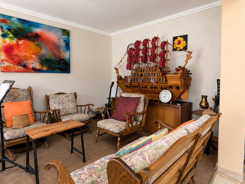 A comfortable living room area featuring neutral wall tones, coving, and carpeted flooring, providing a versatile space for relaxation.