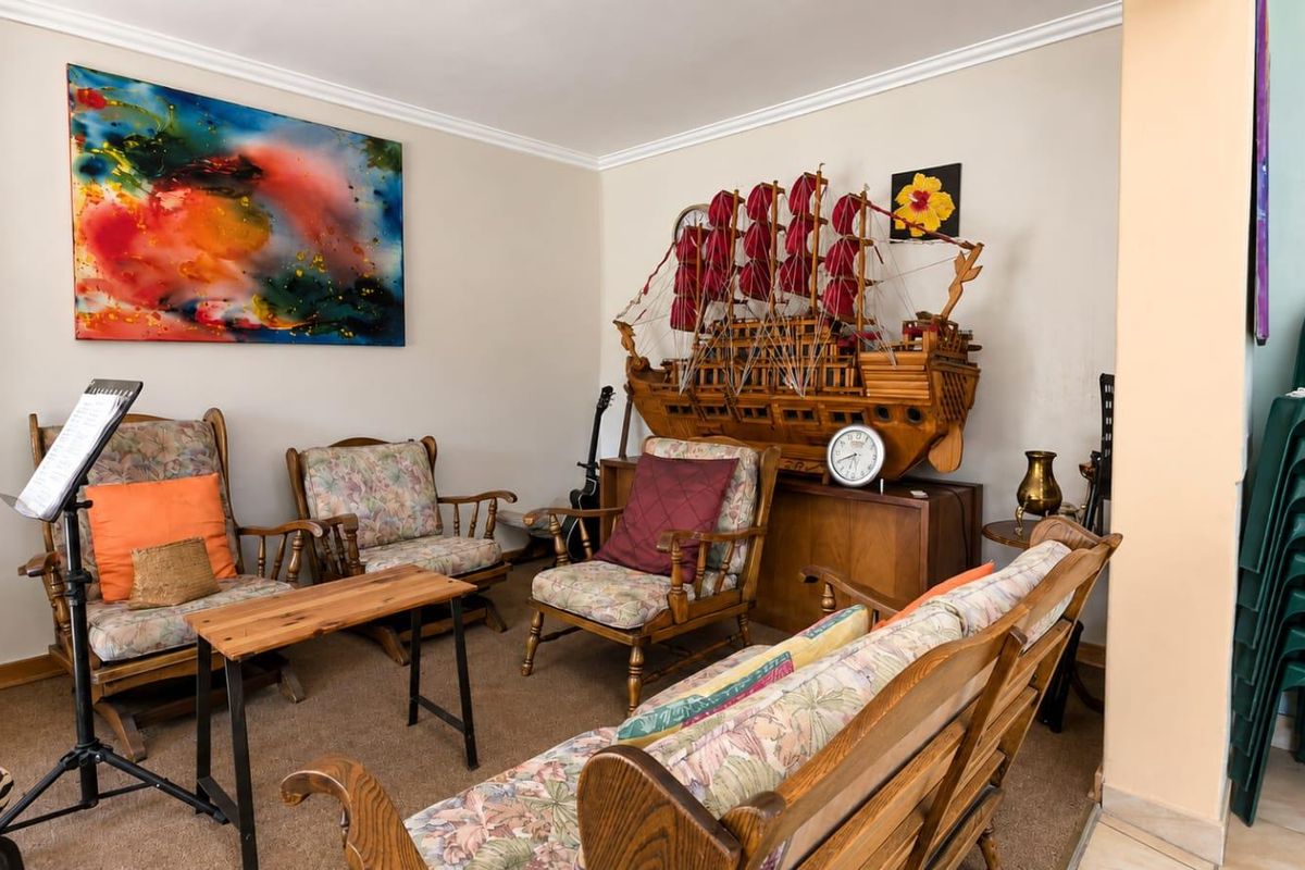 A comfortable living room area featuring neutral wall tones, coving, and carpeted flooring, providing a versatile space for relaxation.