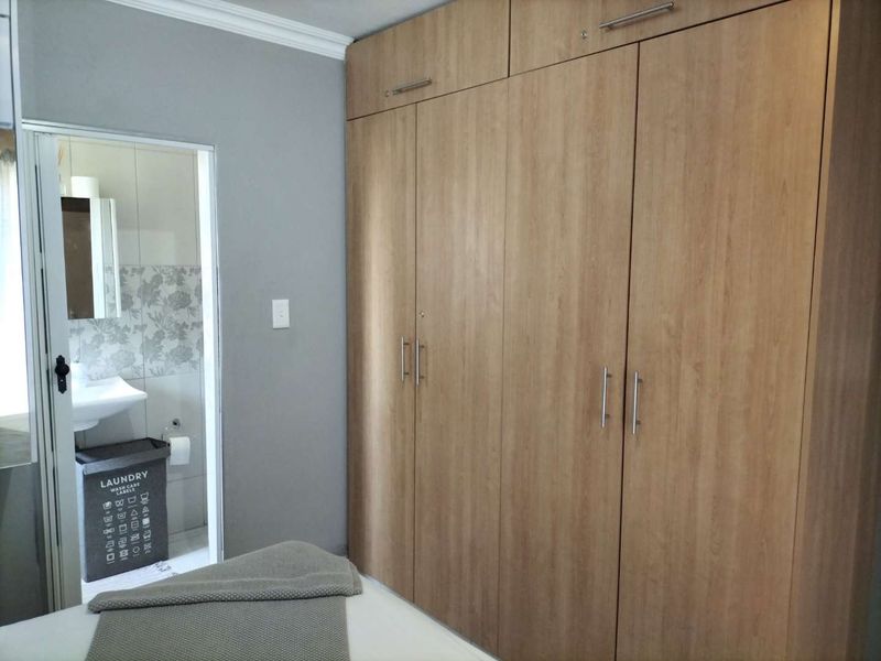 A bedroom featuring floor-to-ceiling built-in wooden cupboards and direct access to an en-suite bathroom.