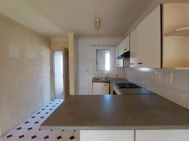 A functional kitchen featuring built-in cabinetry, laminate countertops, a built-in hob, and an extractor fan, offering a blank canvas for renovation.