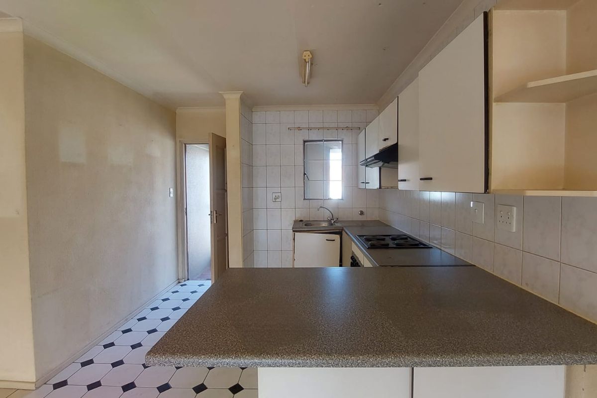 A functional kitchen featuring built-in cabinetry, laminate countertops, a built-in hob, and an extractor fan, offering a blank canvas for renovation.