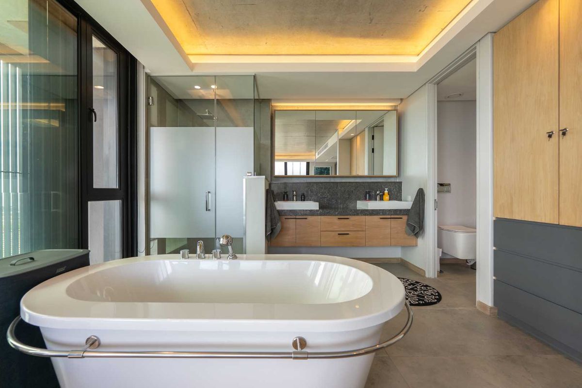 Modern luxury bathroom featuring a freestanding bathtub, double vanity with stone countertop, walk-in shower, and integrated recessed ceiling lighting.