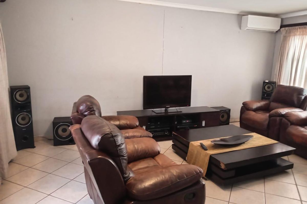 A living room featuring tiled flooring and a wall-mounted air conditioning unit.