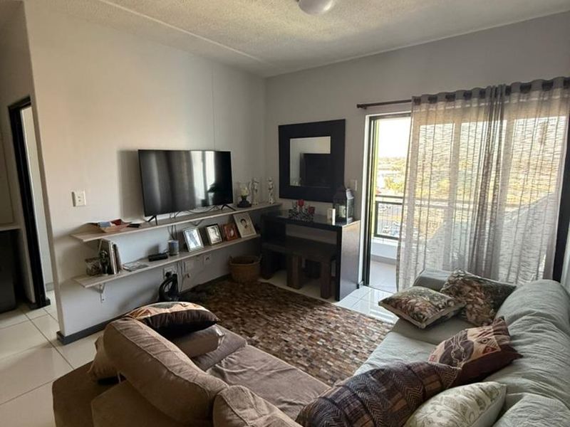 A comfortable living room featuring tiled flooring, built-in shelving, and a sliding glass door providing access to an outdoor balcony area.