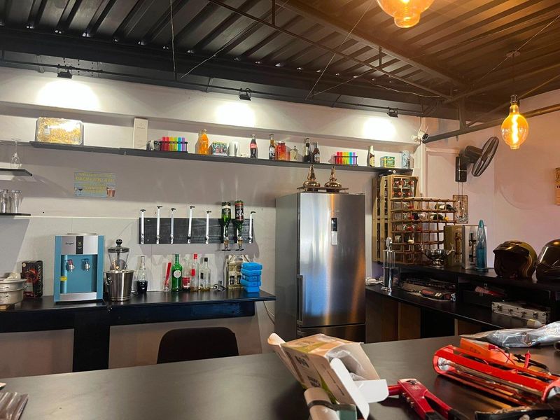 A dedicated home bar area featuring a built-in counter, open shelving, and an industrial-style exposed ceiling with track lighting.