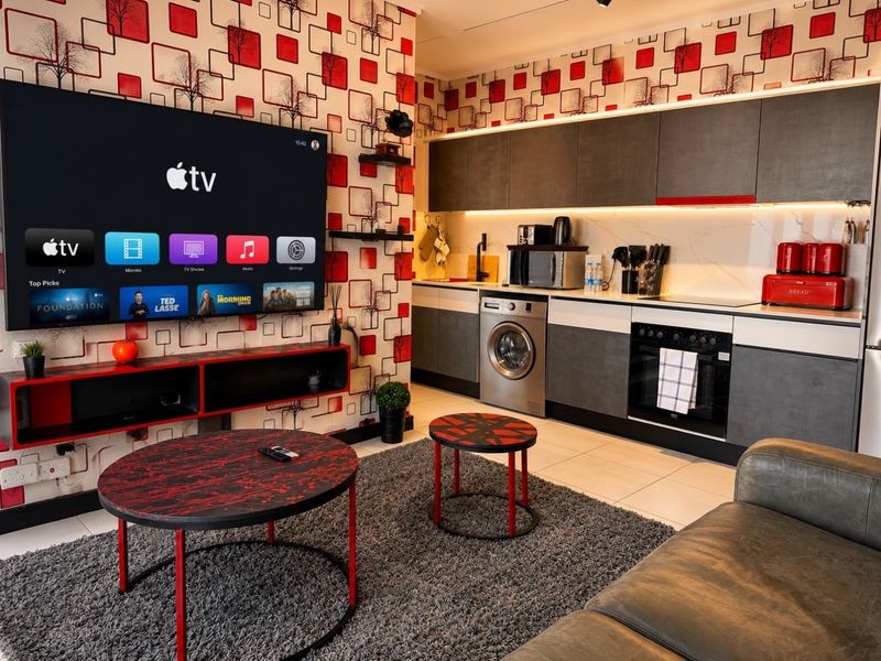 Modern open-plan living area featuring a contemporary kitchen with integrated appliances, sleek cabinetry, and a vibrant feature wall, seamlessly connected to the lounge space.