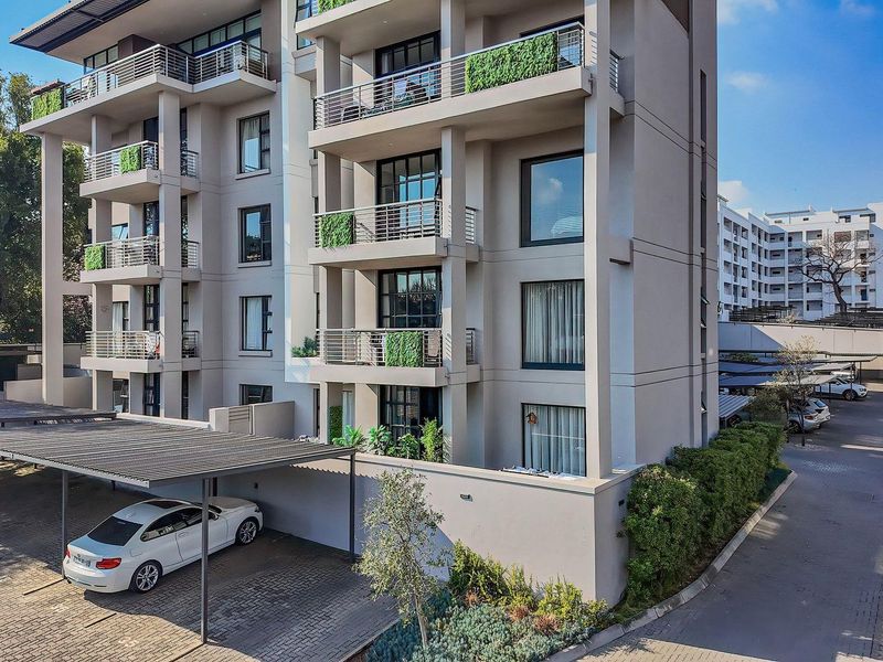 Modern multi-story apartment building featuring private balconies, contemporary facade finishes, and dedicated covered parking bays within a well-maintained complex.