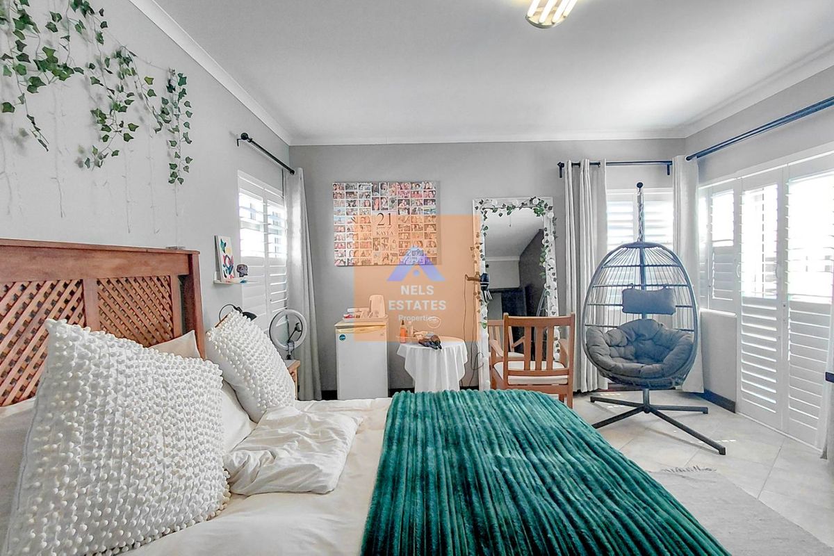 A well-lit bedroom featuring tiled flooring and plantation shutters, offering a bright and comfortable living space.