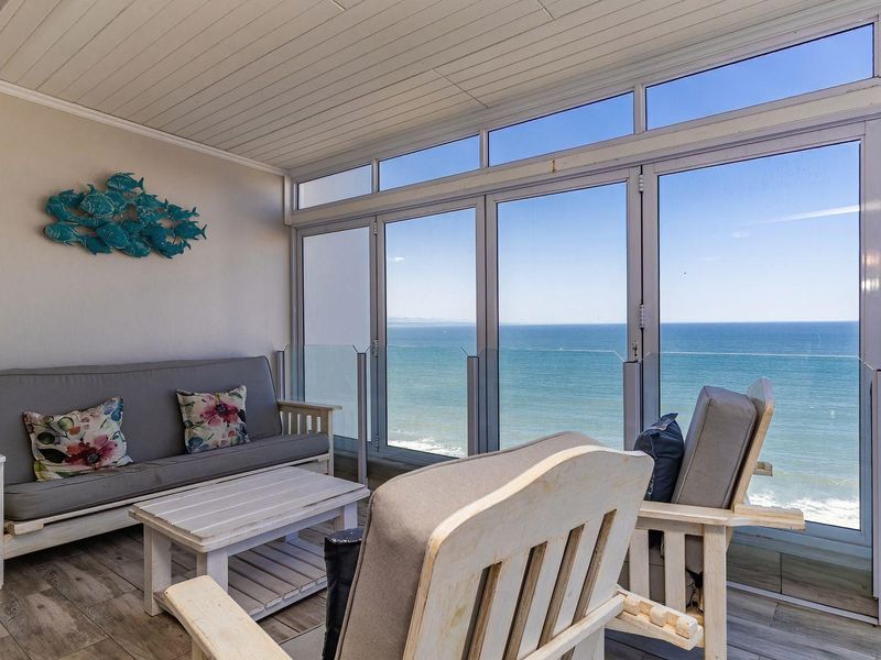 Enclosed balcony featuring large glass sliding doors, tiled flooring, and panoramic ocean views, providing a bright and airy space for relaxation.