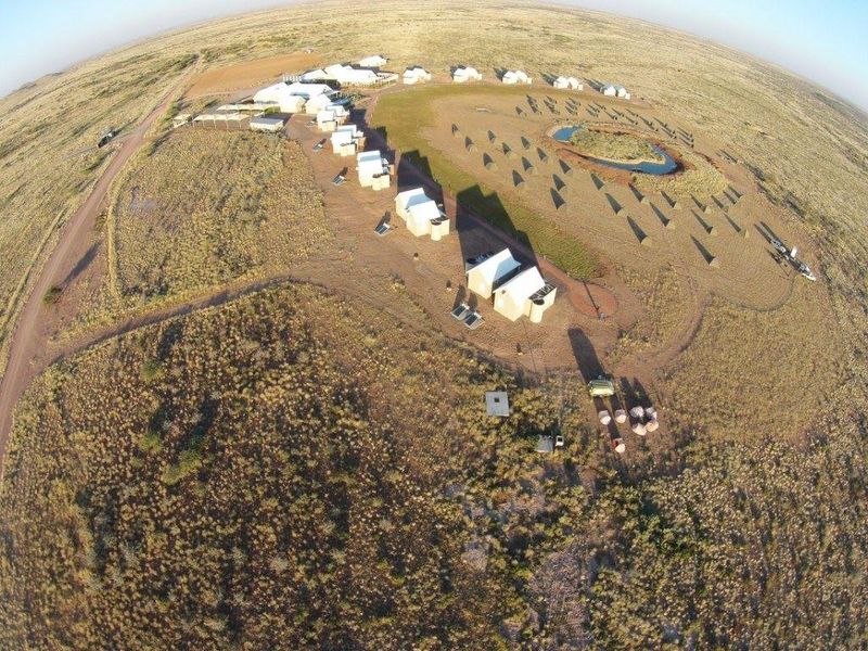 Aerial view of a remote farm property featuring multiple detached buildings, a water reservoir, and extensive surrounding landscape.