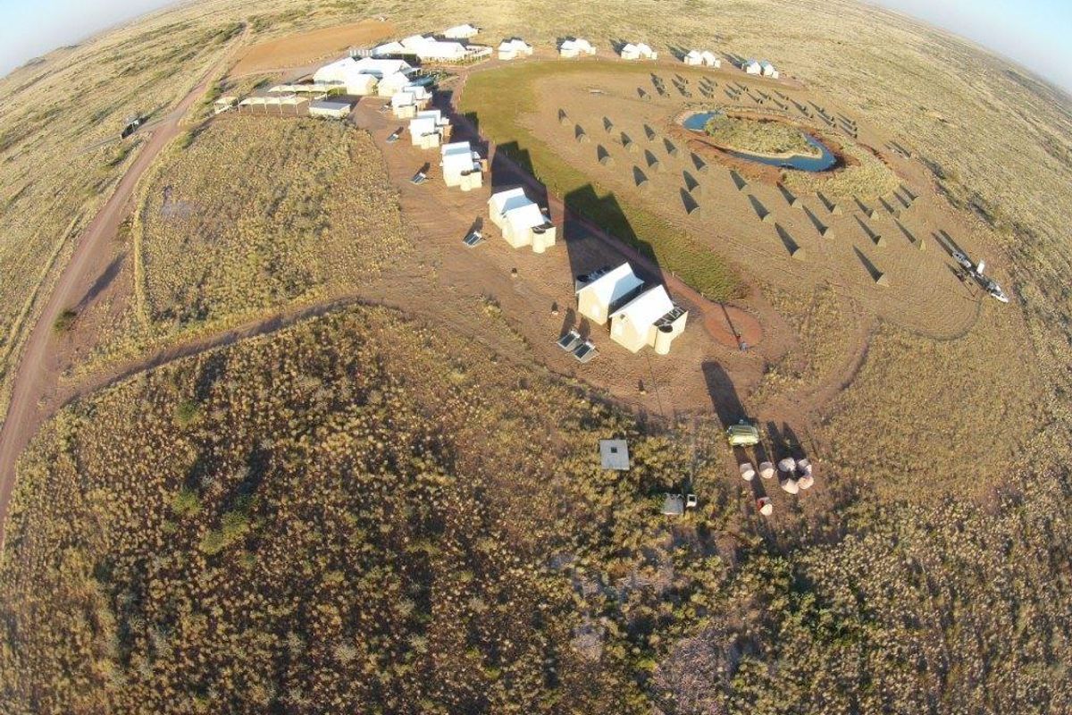 Aerial view of a remote farm property featuring multiple detached buildings, a water reservoir, and extensive surrounding landscape.