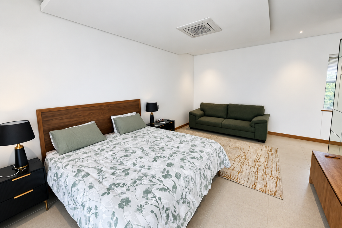 Spacious bedroom featuring tiled flooring, a recessed ceiling with integrated ducted air conditioning, and neutral wall finishes.