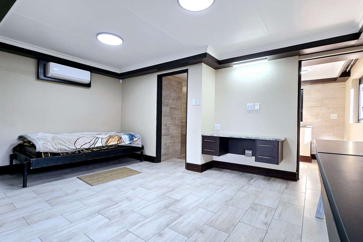 A well-maintained bedroom featuring tiled flooring, a built-in desk, split-system air conditioning, and direct access to an en-suite bathroom.