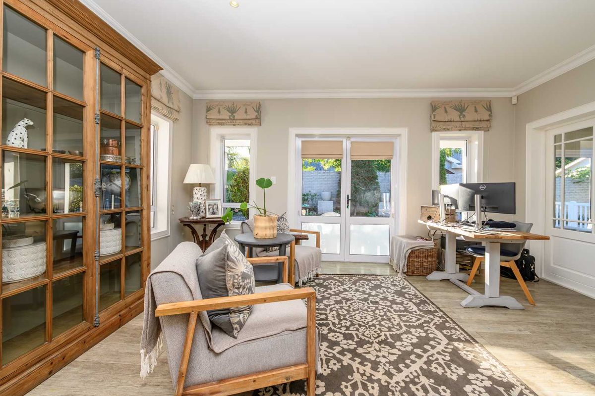 A bright and versatile living space featuring wood-look flooring, built-in cabinetry, and double glass doors providing direct access to the rear garden area.