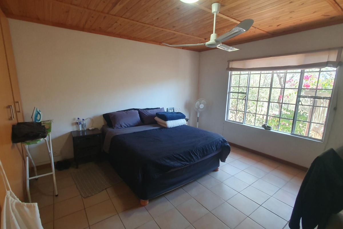 A bedroom featuring tiled flooring, a timber-paneled ceiling, a ceiling fan, and built-in wooden cupboards.