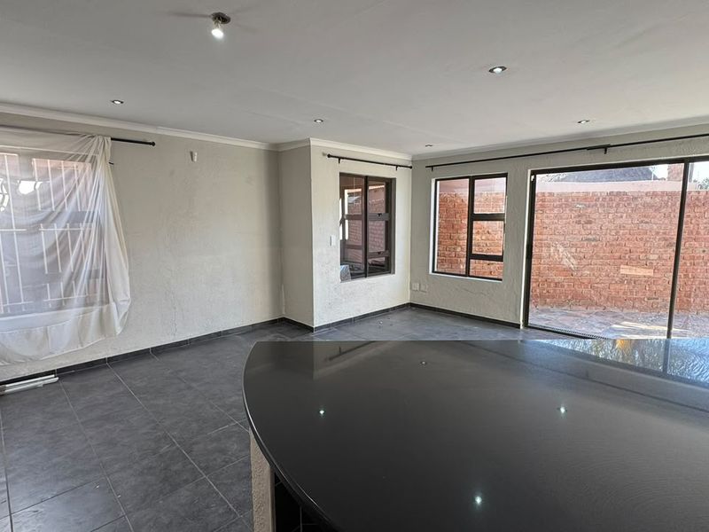 Spacious open-plan living area featuring dark tiled flooring, recessed lighting, and a large granite kitchen island, with direct access to the rear patio.