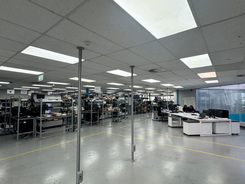 Spacious industrial open-plan office or workshop area featuring suspended acoustic ceiling tiles, recessed lighting, and durable epoxy-coated flooring.