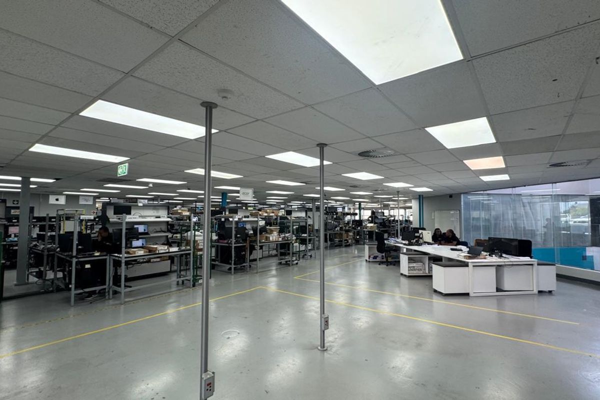 Spacious industrial open-plan office or workshop area featuring suspended acoustic ceiling tiles, recessed lighting, and durable epoxy-coated flooring.