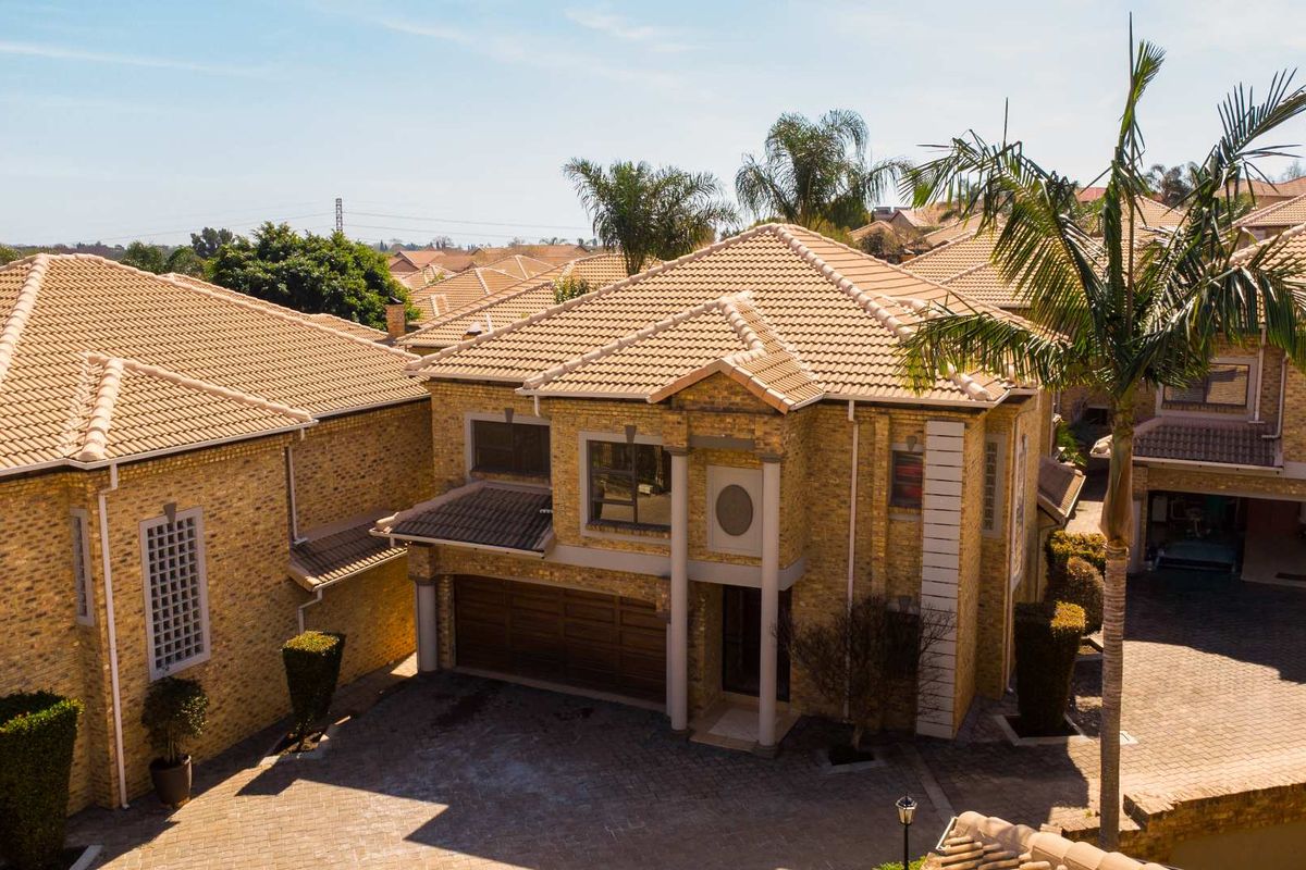 Aerial view of a multi-story townhouse complex featuring brick facades, tiled roofs, and paved driveway access.