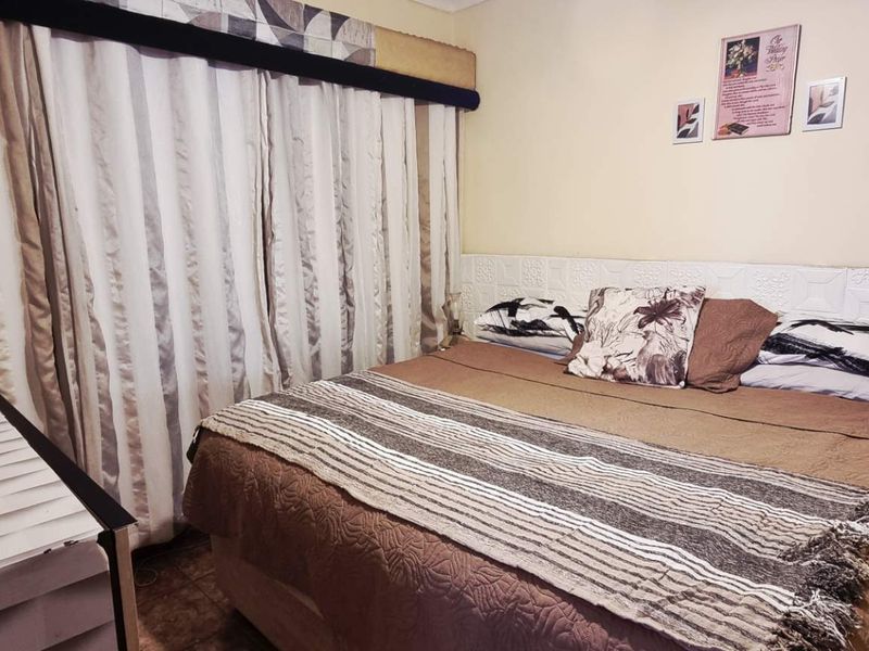A bedroom featuring textured wall paneling and tiled flooring, providing a functional space with neutral tones.
