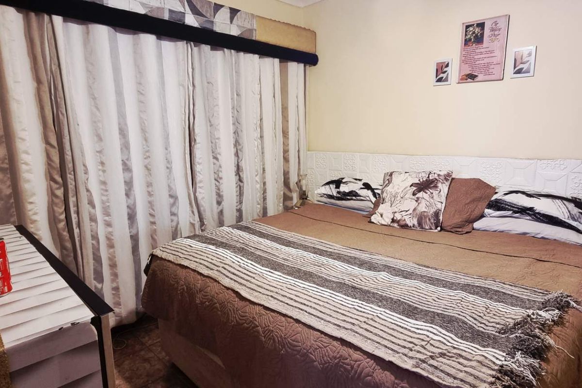 A bedroom featuring textured wall paneling and tiled flooring, providing a functional space with neutral tones.