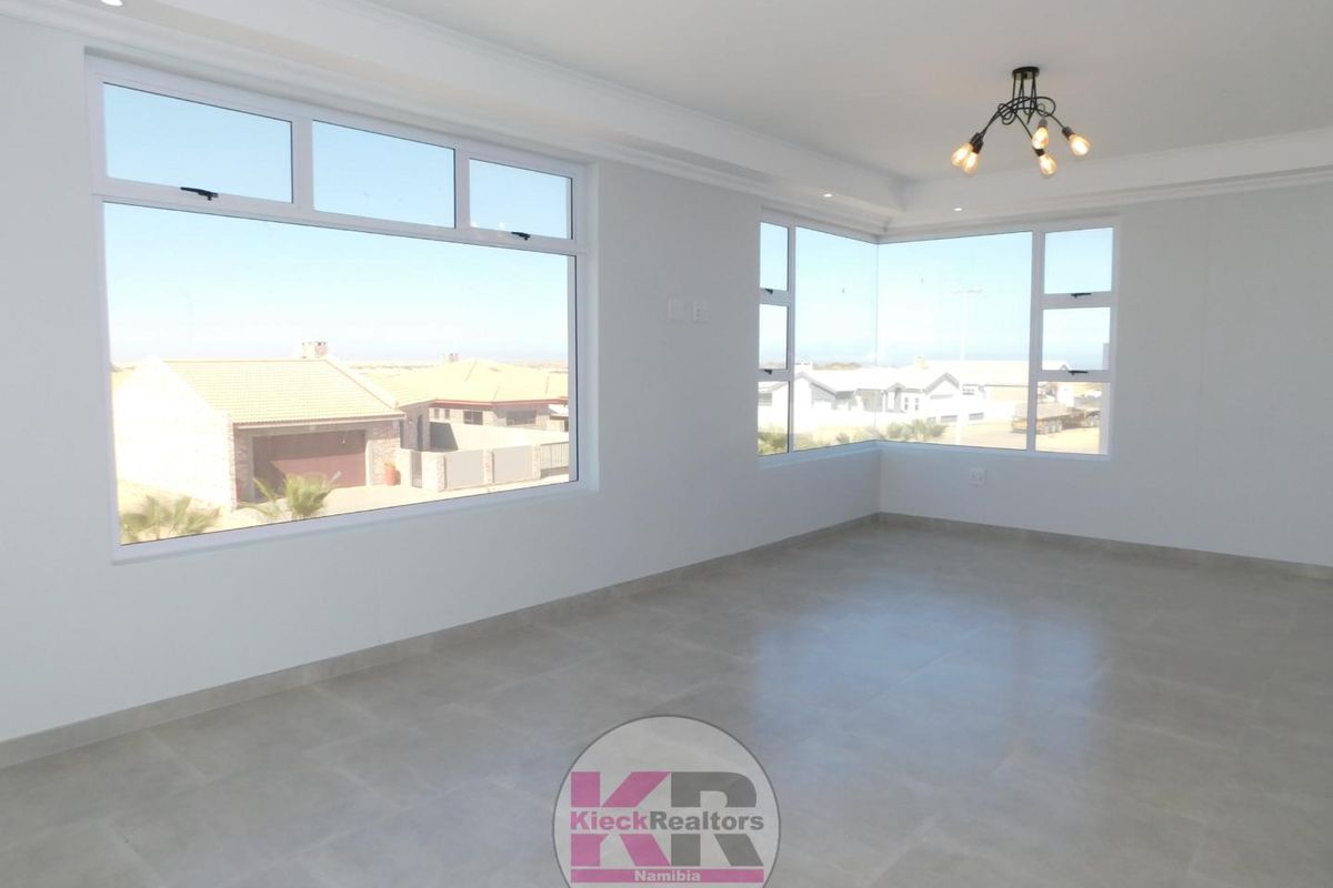 Bright and spacious living area featuring large windows, neutral tiled flooring, and modern recessed ceiling lighting.