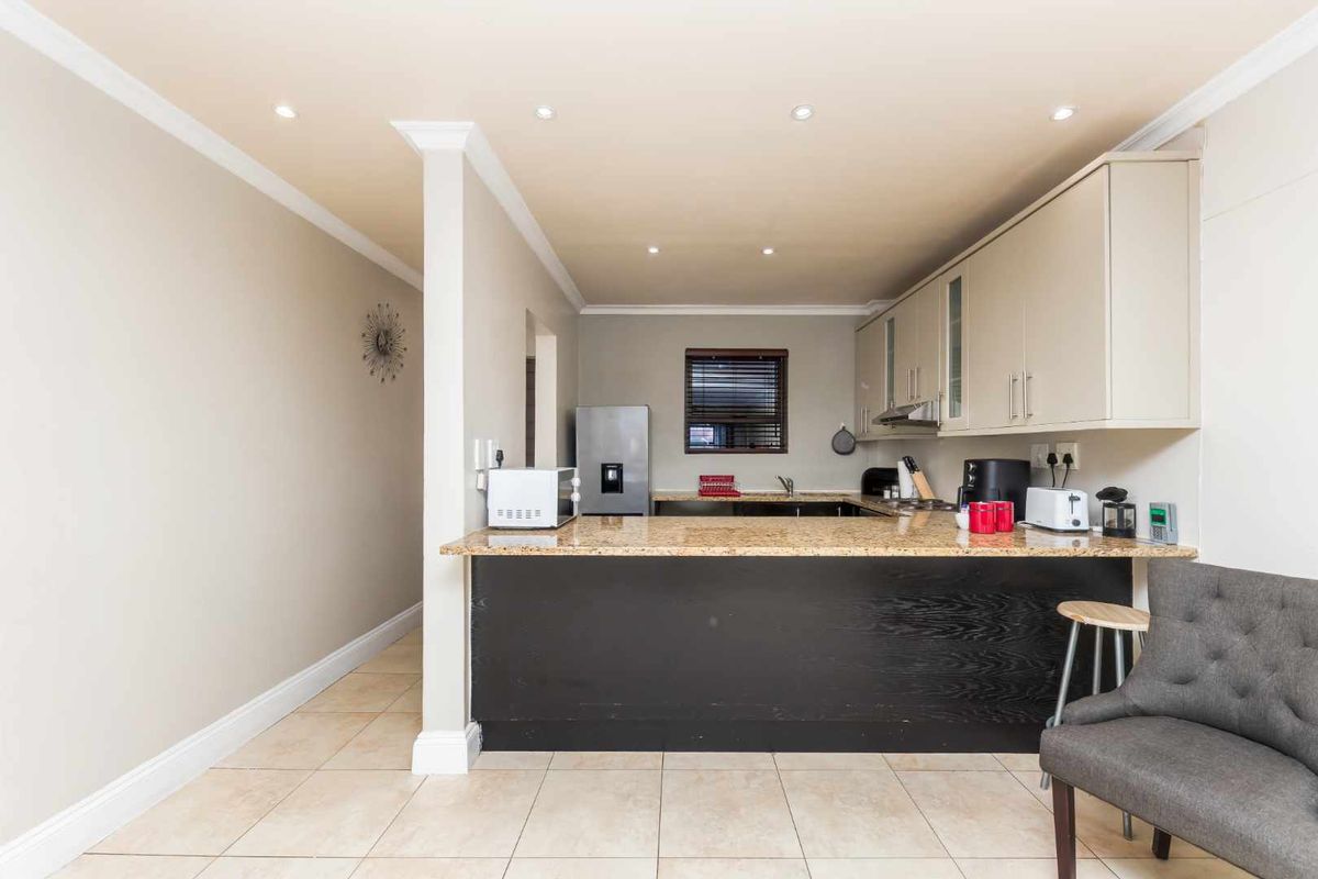 A functional kitchen featuring granite countertops, ample built-in cabinetry, a breakfast bar, and tiled flooring with recessed lighting.
