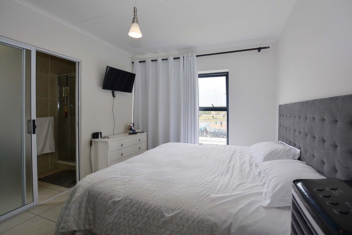 A well-maintained bedroom featuring tiled flooring, a pendant light, and an integrated en-suite bathroom with a sliding door entrance.