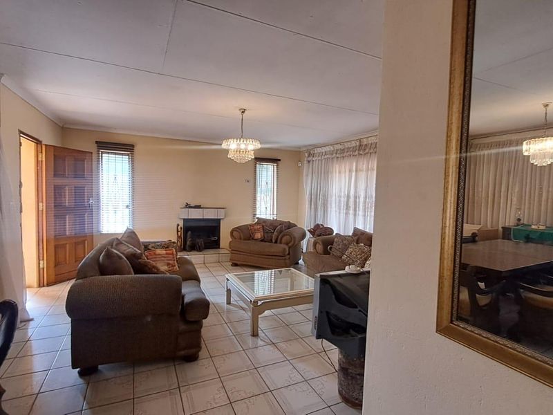 Spacious living room featuring tiled flooring, a built-in fireplace, and natural light through large windows, offering a comfortable and functional living space.
