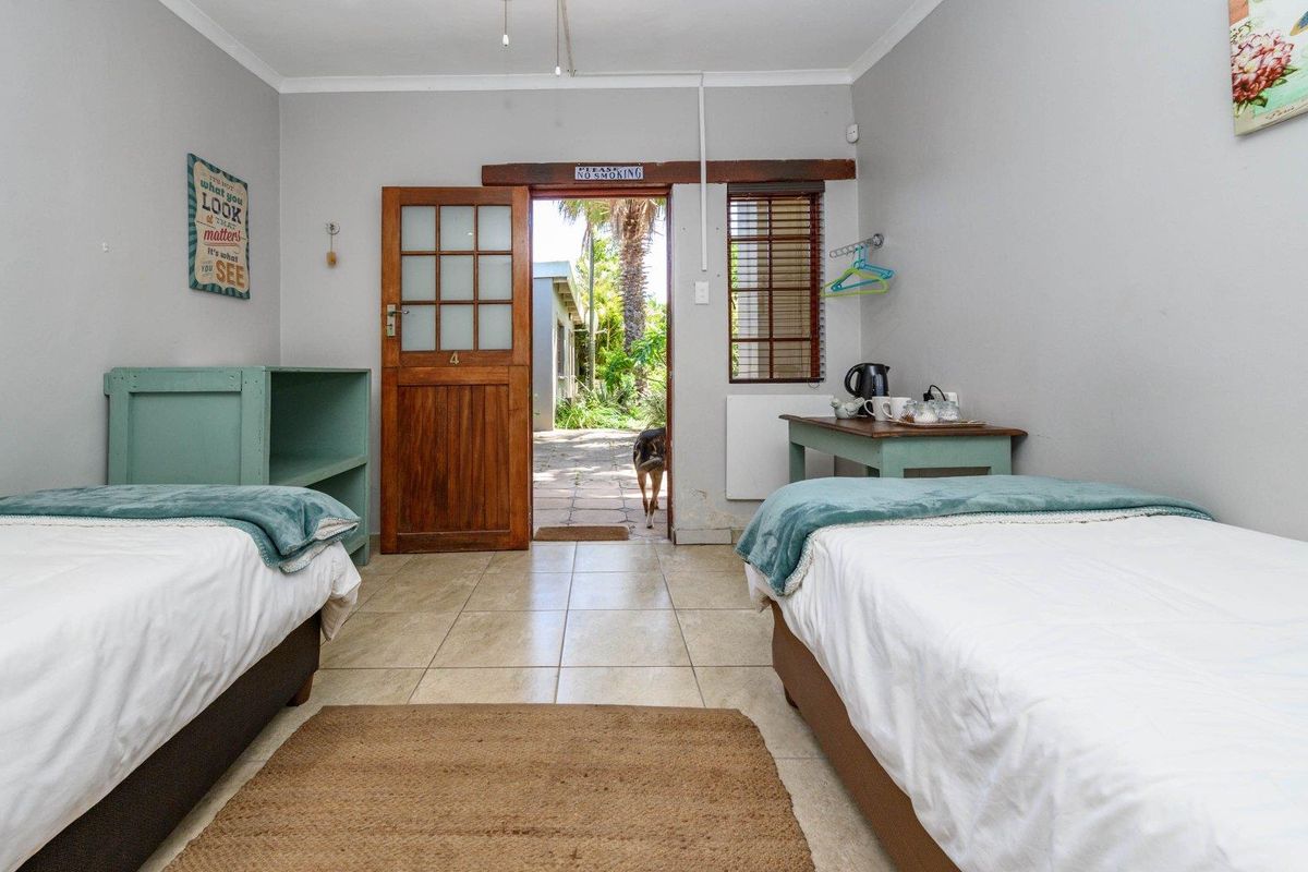 A bedroom featuring tiled flooring and direct access to an outdoor patio area through a timber framed door.
