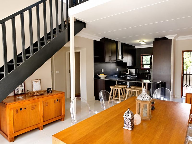 Open plan living and dining area featuring a modern kitchen with dark cabinetry, tiled floors, and a staircase leading to the upper level.